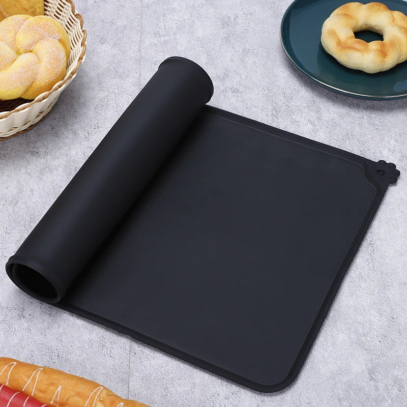 Tapis de gamelle noir en silicone souple partiellement enroulé, imperméable et antidérapant pour chien et chat, avec rebord anti-débordement et motif patte d'animal.