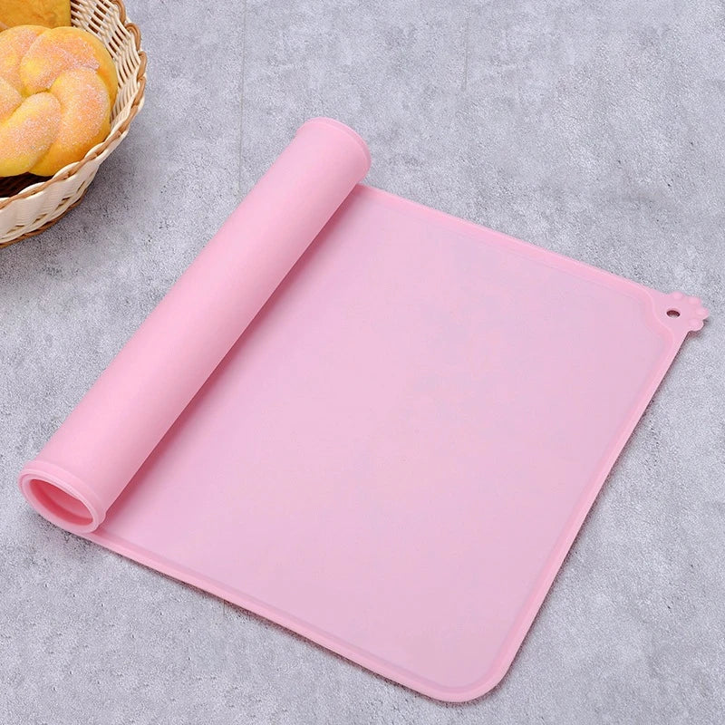 Tapis de gamelle rose en silicone souple partiellement enroulé, imperméable et antidérapant pour chien et chat, avec rebord anti-débordement et motif patte d'animal.