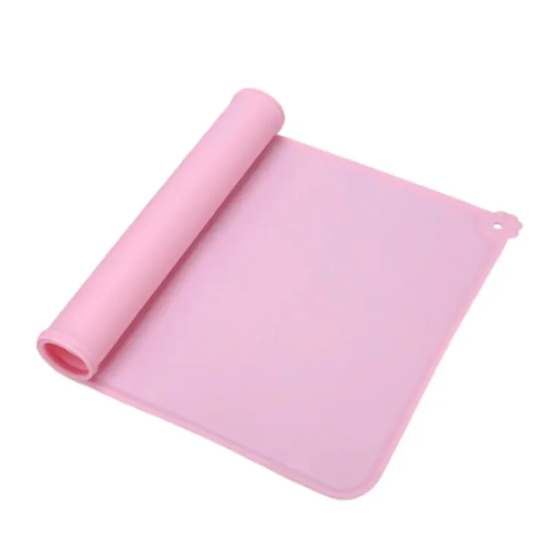 Tapis de gamelle rose en silicone souple partiellement enroulé, imperméable et antidérapant pour chien et chat, avec rebord anti-débordement et détail patte d'animal.