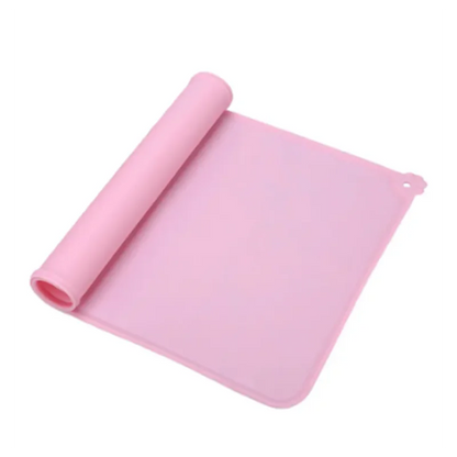 Tapis de gamelle rose en silicone souple partiellement enroulé, imperméable et antidérapant pour chien et chat, avec rebord anti-débordement et détail patte d'animal.