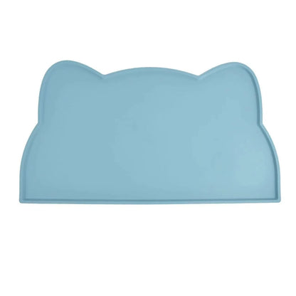 Photographie de face sur fond blanc du tapis gamelles chat en silicone bleu azur de la marque Les Trésors d'Owka. Ce tapis chat arbore un design original en forme de tête de félin avec des bords surélevés conçus pour stopper les débordements d'eau et de nourriture. Fabriqué en silicone alimentaire antidérapant et imperméable, ce tapis gamelles protège efficacement vos parquets et carrelages tout en facilitant l'entretien du coin repas. Sa couleur bleue pastel et sa finition mate en font un accessoire de dom