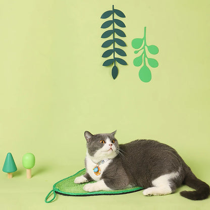 Tapis griffoir pour chat en sisal naturel en forme d'avocat vert, avec un chat gris et blanc allongé dessus dans un décor végétal minimaliste.