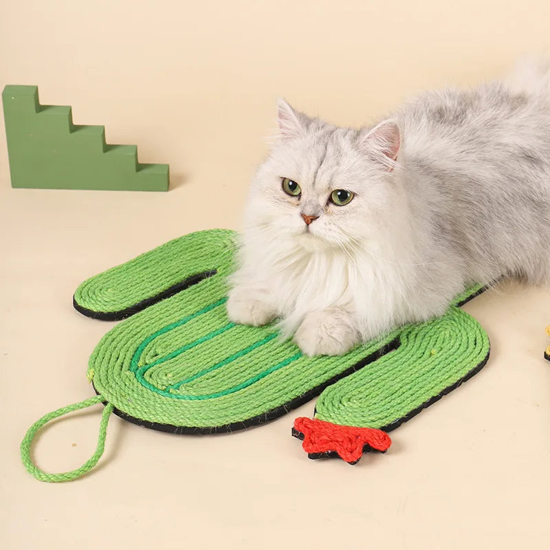 Tapis griffoir pour chat en sisal naturel en forme de cactus vert avec une fleur rouge, sur lequel repose un chat blanc à poil long, utilisable au sol ou en fixation murale.