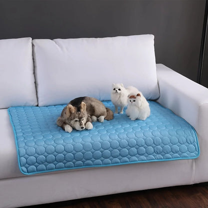 Tapis rafraichissant chien et chat bleu matelassé posé sur un canapé blanc pour protéger le mobilier. L'image illustre ce tapis rafraichissant chat souple et respirant utilisé comme protection de sofa. Matelas d'été polyvalent et confortable, idéal comme coussin rafraichissant pour chat. Qualité Les Trésors d'Owka.