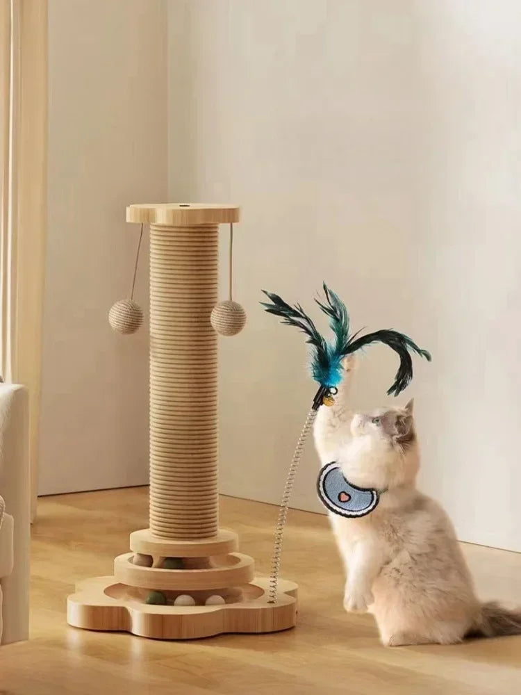 Chat à poils longs jouant avec un plumeau bleu sur ressort intégré à une tour de jeu en bois comprenant un poteau à griffer en sisal et un circuit de balles à la base.