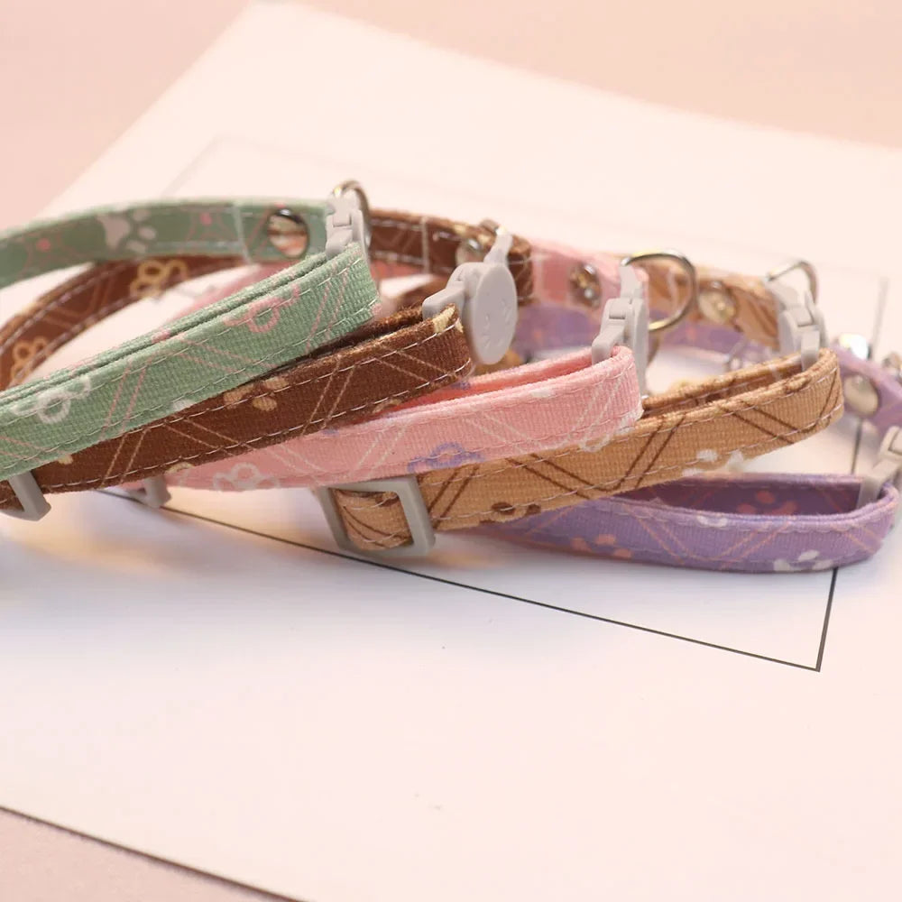 Détails rapprochés de colliers pour chat aux motifs floraux et géométriques. Visuel montrant la boucle de sécurité anti-étranglement en forme de tête de chat et le tissu résistant. Ce collier chaton réglable est disponible en plusieurs coloris pastel. Finition haut de gamme pour la sécurité des animaux. Les Trésors d'Owka.