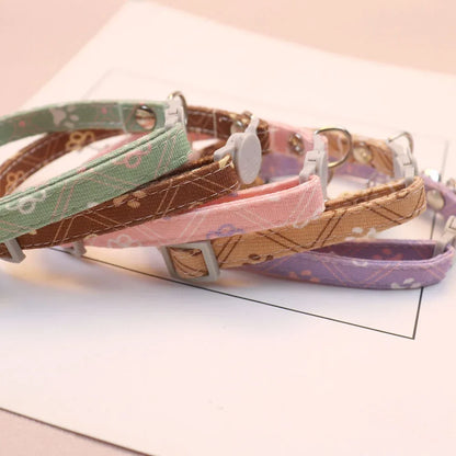 Détails rapprochés de colliers pour chat aux motifs floraux et géométriques. Visuel montrant la boucle de sécurité anti-étranglement en forme de tête de chat et le tissu résistant. Ce collier chaton réglable est disponible en plusieurs coloris pastel. Finition haut de gamme pour la sécurité des animaux. Les Trésors d'Owka.