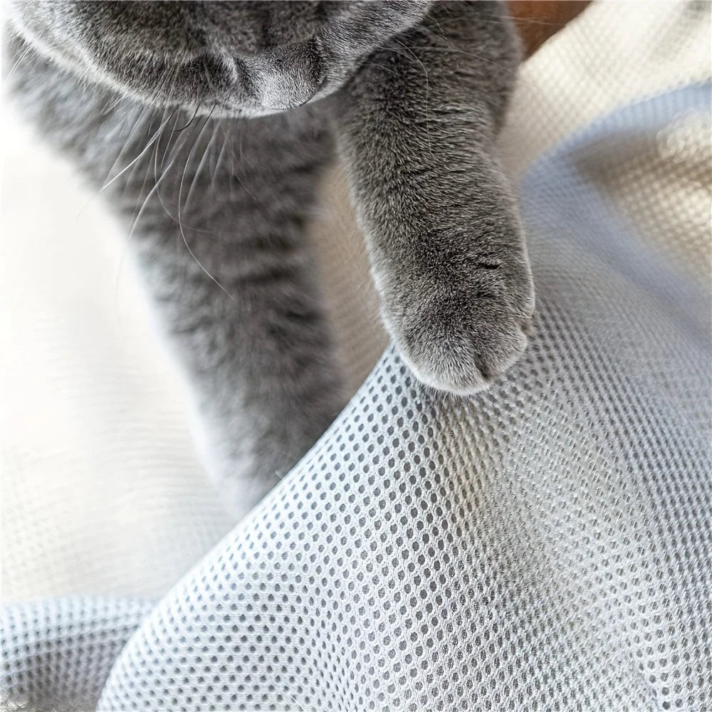 Gros plan macro d'une patte de chat sur le tissu mesh gris d'un hamac chat surélevé. L'image montre la texture alvéolée respirante et résistante de ce coussin à chat technique. Alternative durable au coussin pour chat classique, facile à laver et anti-odeurs. Qualité Les Trésors d'Owka.